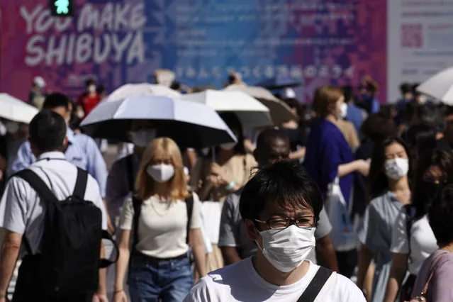 People wearing a protective face mask to help curb the spread of the coronavirus walk at Shibuya pedestrian crossing in Tokyo Thursday, July 2, 2020. Japan lifted a seven-week pandemic state emergency in late May, and social and business activity have since largely resumed. (Photo by Eugene Hoshiko/AP Photo)