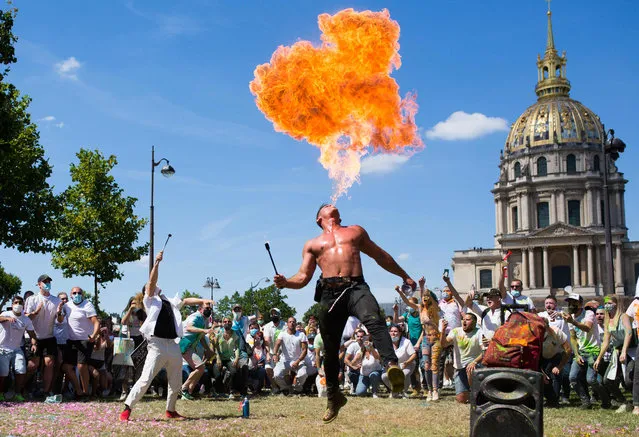 A fire eater performs as nightclub workers demonstrate on July 12, 2020 in Paris near the Health ministry to ask the reopening of their venues. Nightclubs closure and summer festival cancellations have been imposed as part of lockdown measures to curb the spread of the COVID-19 (novel coronavirus) pandemic, while many sectors in France have seen their restrictions progressively lifted. (Photo by Raphael Lafargue/AFP Photo)