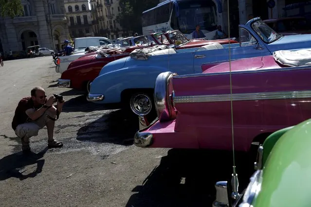 A tourist takes photographs of vintage cars in Havana September 18, 2015. (Photo by Carlos Garcia Rawlins/Reuters)