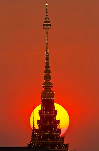 The sun sets behind a tower under construction for the cremation of Cambodia's late King Norodom Sihanouk, near the Royal Palace in Phnom Penh, January 18, 2013. The Royal Palace is scheduled to hold a rehearsal for Sihanouk's funeral on January 19. The former king died on October 15, 2012. He was 89. (Photo by Heng Sinith/Associated Press)