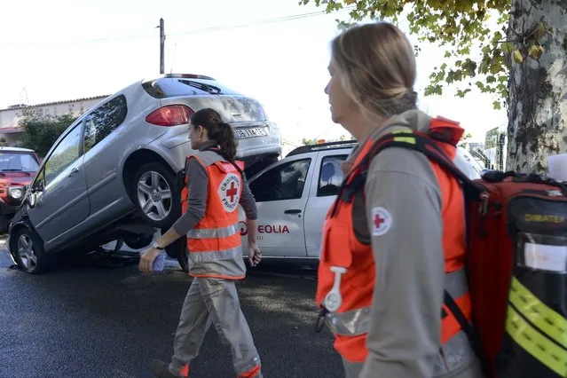 French Red Cross volunteers walk past an upended car on a street after flooding caused by torrential rain in Biot, France, October 4, 2015. (Photo by Jean-Pierre Amet/Reuters)