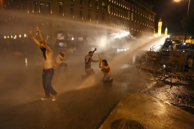 Protesters gesture with the victory sign while sprayed by water from police water cannons in Martyr square, downtown Beirut, Lebanon October 8, 2015. (Photo by Aziz Taher/Reuters)