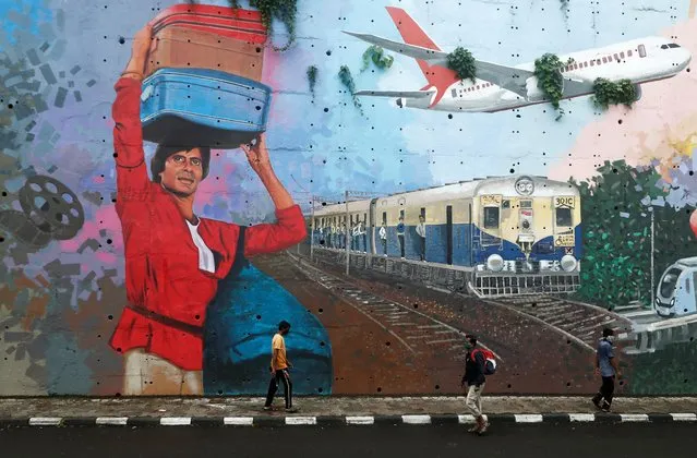 People wearing protective masks walk past a mural of Bollywood actor Amitabh Bachchan, after he and other members of his family tested positive for the coronavirus disease (COVID-19) in Mumbai, July 13, 2020. (Photo by Francis Mascarenhas/Reuters)