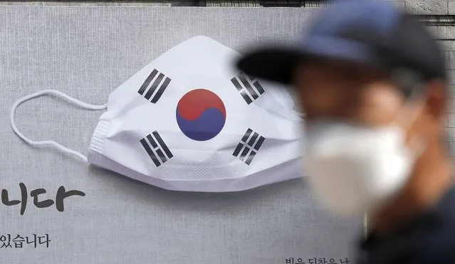 A man wearing a face mask walks near a banner displaying as a part of campaign to overcome the coronavirus in Seoul, South Korea, Friday, September 4, 2020. (Photo by Lee Jin-man/AP Photo)