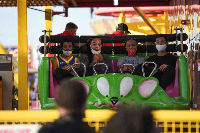 Youths with masks begin a ride at the Mississippi State Fair as it opens with coronavirus disease (COVID-19) restrictions in Jackson, Mississippi, U.S., October 7, 2020. (Photo by Rory Doyle/Reuters)