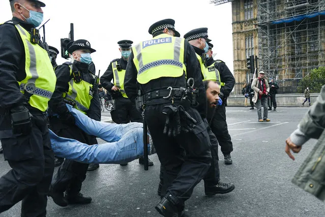 Police detain a man, during a coronavirus anti-lockdown protest on Westminster Bridge, in London, Saturday, October 24, 2020. (Photo by Alberto Pezzali/AP Photo)