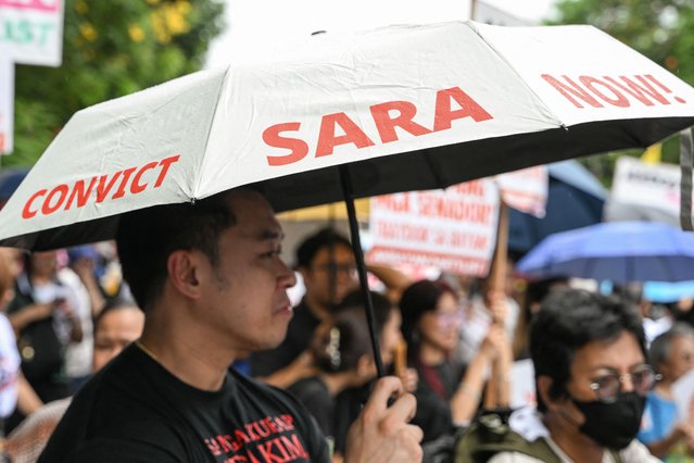 A man holds an umbrella reading “Convict Sara Now!” as people gather to protest following the Senate's decision on the impeachment trial of Philippine Vice President Sara Duterte, outside the Senate of the Philippines in Pasay, Metro Manila on June 11, 2025. House of Representatives prosecutors said on June 11 that Philippine Vice President Sara Duterte's impeachment trial could not be stopped despite the Senate sending the case back to them hours after convening as a court. (Photo by Jam Sta Rosa/AFP Photo)