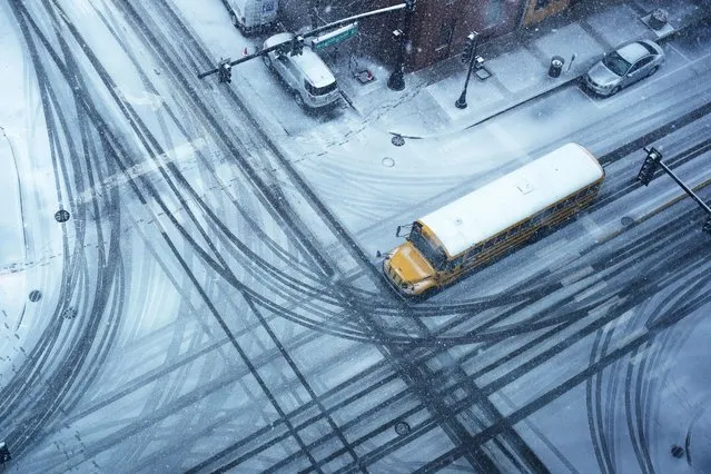 A school bus crosses a snow-covered intersection, Thursday, February 16, 2023, in Waukegan, Ill. (Photo by Nam Y. Huh/AP Photo)