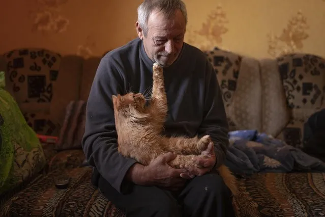 Land mine victim Oleksandr Rabenko, 66 years-old, pauses during an interview with the Associated Press as Murzik, his cat, touches his face on the outskirts of Izium, Ukraine, Sunday, February 19, 2023. In this war-scarred city in Ukraine's northeast, residents scrutinize every step for land mines. The brutality of the Russian invasion in this one-time strategic supply hub for Russian troops counts among the most horrific of the war, which entered its second year last month. (Photo by Vadim Ghirda/AP Photo)