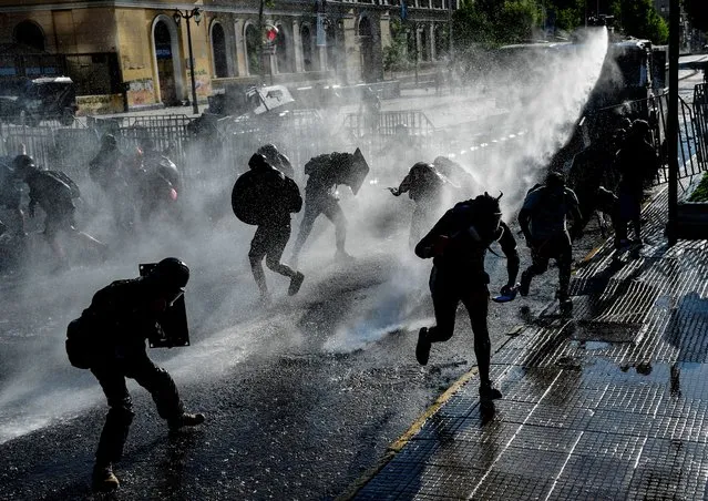 Demonstrators are sprayed by a riot police water cannon during clashes following a protest against Chilean President Sebastian Pinera's government in Santiago, on November 28, 2020. (Photo by Martin Bernetti/AFP Photo)