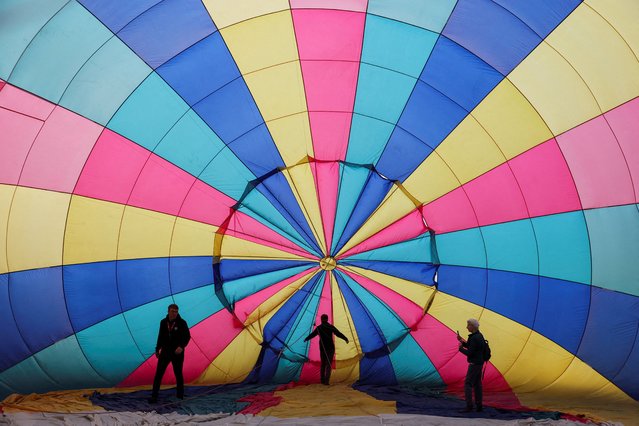 Crew members inflate a hot air balloon during a mass launch at the annual Bristol International Balloon Fiesta, in Bristol, Britain, on August 8, 2025. (Photo by Toby Melville/Reuters)