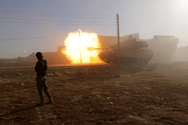 A rebel fighter stands near a Turkish tank as it fires towards Guzhe village, northern Aleppo countryside, Syria October 17, 2016. (Photo by Khalil Ashawi/Reuters)