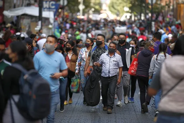 Shoppers, the vast majority wearing protective face masks, crowd a street in a commercial district of central Mexico City, Saturday, December 5, 2020. With hospitals once again filling up with COVID-19 patients, Mexico City's mayor on Friday urged people to stay at home as much as possible and authorized checkpoints to limit the number of people entering the capital's colonial-era downtown at one time. (Photo by Rebecca Blackwell/AP Photo)