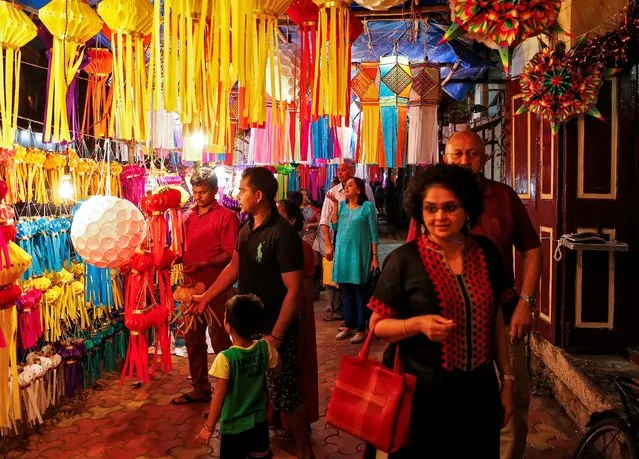 Customers stand under lanterns for sale as they look at them at a roadside market ahead of the Hindu festival of Diwali in Mumbai, India, October 23, 2016. (Photo by Danish Siddiqui/Reuters)