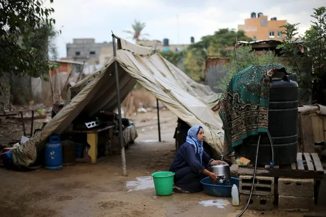 A Palestinian woman, whose house was destroyed by what witnesses said was Israeli shelling during a 50-day war in the summer of 2014, washes a cooker outside her makeshift shelter on a rainy day, in Khan Younis in the southern Gaza Strip October 8, 2015. (Photo by Ibraheem Abu Mustafa/Reuters)