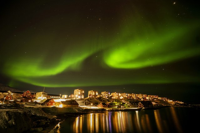 The northern lights appear over homes in Nuuk, Greenland, Monday, February 17, 2025. (Photo by Emilio Morenatti/AP Photo)