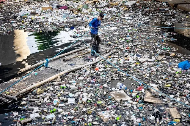 A “river warrior” collects plastic waste at San Juan river on April 20, 2023 in Manila, Philippines. The Philippines is the largest ocean polluter in the world, contributing a third of the 80% of global ocean plastic that comes from Asian rivers, according to a 2021 report by Oxford University's Our World in Data. Poverty has led the Philippines to become a “sachet economy” that consumes 163 million sachets every day, worsening marine plastic pollution in the region. The trash is piling up on land, clogging coastlines, spilling into the sea, and traveling to remote corners of the globe, as the country fails to meet targets for improved waste management that it signed into law more than two decades ago. According to Greenpeace, global corporations trap low-income customers in developing countries like the Philippines to buy – and buy often – fast-moving consumer goods in small quantities packaged in cheap, disposable plastics as part of a strategy to drive market share and profits. Break Free From Plastic’s 2022 Brand Audit Report revealed that the Coca-Cola Company, Philip Morris International, Universal Robina Corporation (URC), Philippine Spring Water Resources, Inc., and Japan Tobacco International are the worst plastic polluters in the country. Globally, Coca-Cola also leads the list for five years in a row, followed by PepsiCo, Nestle, Mondelez International, and Unilever – all consistently part of the annual top 10. (Photo by Ezra Acayan/Getty Images)