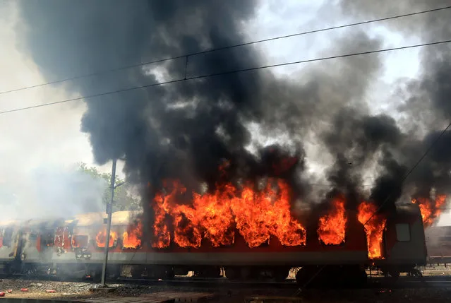 Smoke and fire billows out from a coach of a passenger train after it caught fire near Birlanagar railway station in Gwalior, India, May 21, 2018. (Photo by Reuters/Stringer)
