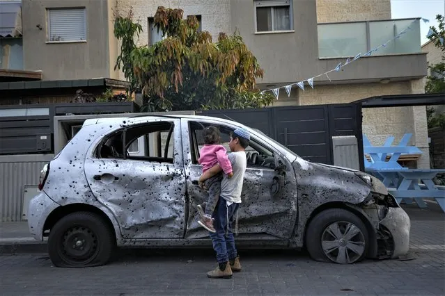 Israeli kids look at a car hit by a rocket fired from the Gaza Strip, at the southern Israeli city of Sderot, Tuesday, May 2, 2023. The Israeli military says that Palestinian militants in Gaza have fired a barrage of rockets following the death of Khader Adnan, a high-profile Palestinian prisoner in Israeli custody after a nearly three-month-long hunger strike. (Photo by Ohad Zwigenberg/AP Photo)