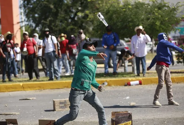 An activist throws bottles against the military police officers during a demonstration at the military zone of the 27th infantry battalion in Iguala, Guerrero, January 12, 2015. (Photo by Jorge Dan Lopez/Reuters)