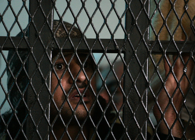 A suspected al Qaeda militant reacts from behind bars as his verdict is being pronounced at the state security court of appeals in Sanaa March 26, 2013. (Photo by Khaled Abdullah/Reuters)