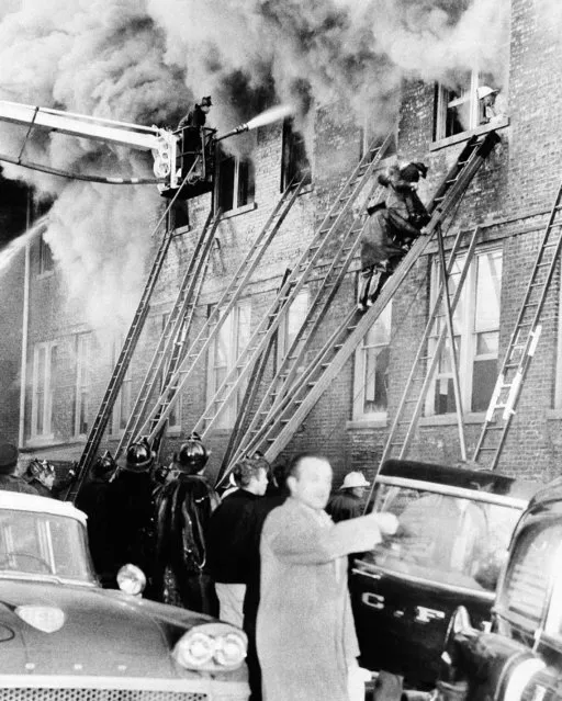 Smoke billows from upper floor of Our Lady of the Angels parochial school on December 2, 1958 in Chicago where about 90 pupils and teachers perished yesterday in a flash fire. Schoolboy is brought down ladder at the Roman Catholic grade school on city's northwest side. (Photo by AP Photo)