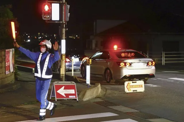 A police officer directs traffic near a building where a man is holed up in Nakano, central Japan, Thursday, May 25, 2023. Multiple people including a few police officers were killed in Nakano, a city in Nagano prefecture, in central Japan on Thursday and a suspect with a rifle and knife was holed up inside a house, police said. (Photo by Takuto Kaneko/Kyodo News via AP Photo)