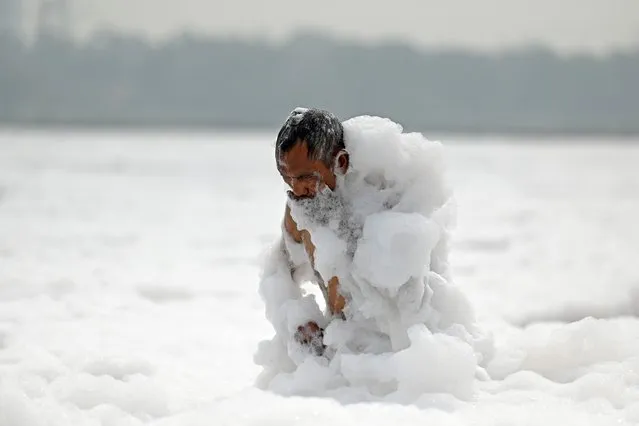 A man bathes in the polluted waters of river Yamuna laden with foam, on the eve of world environment day in New Delhi on June 4, 2023. (Photo by Arun Sankar/AFP Photo)