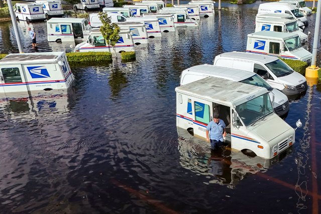 A USPS worker inspects trucks that had been relocated to protect them from wind but which are now underwater as intense rain from Hurricane Milton caused the Anclote River to flood, Friday, October 11, 2024, in New Port Richey, Fla. (Photo by Mike Carlson/AP Photo)