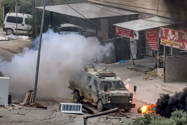 An explosive charge left by Palestinians detonates by an Israeli armoured vehicle during an Israeli army raid in Jenin in the occupied West Bank on June 19, 2023. Violent clashes erupted in Jenin on June 19 during an Israeli raid on the West Bank city in which the army fired missiles from a helicopter, according to an AFP photographer at the scene. (Photo by Jaafar Ashtiyeh/AFP Photo)