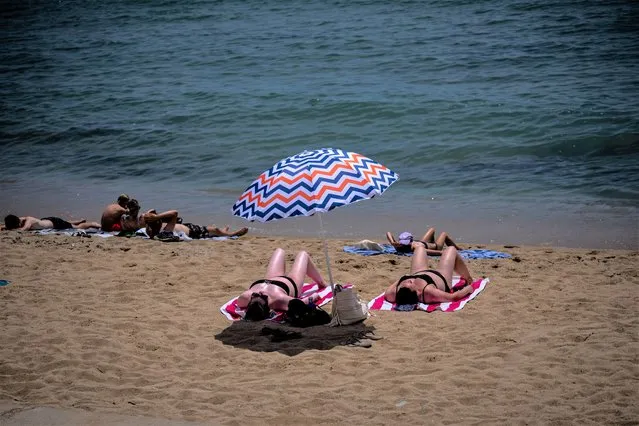 People sunbathe on a beach in Barcelona, Spain, Monday, July 17, 2023. Spain's Aemet weather agency said a heatwave starting Monday “will affect a large part of the countries bordering the Mediterranean” with temperatures in some southern areas of Spain exceeding 42-44 ºC. (Photo by Emilio Morenatti/AP Photo)