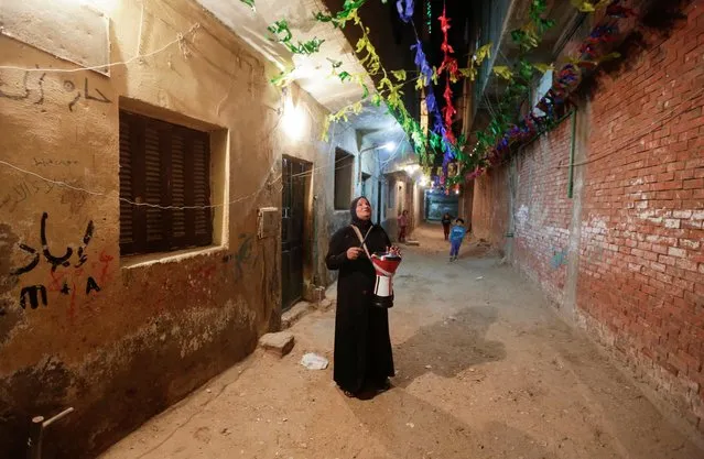 Hajja Dalal, a 46-year-old Mesaharati, beats a drum to wake up Muslims to have the pre-dawn meal before they start their long-day fast during Ramadan at Maadi neighbourhood in Cairo, Egypt on April 13, 2021. (Photo by Hayam Adel/Reuters)