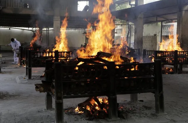 Flames rise from cremation pyres of victims of a fire that broke out in Vijay Vallabh COVID-19 hospital, at Virar, near Mumbai, India, Friday, April 23, 2021. A fire killed 13 COVID-19 patients in a hospital in western India early Friday as an extreme surge in coronavirus infections leaves the nation short of medical care and oxygen. (Photo by Rajanish Kakade/AP Photo)