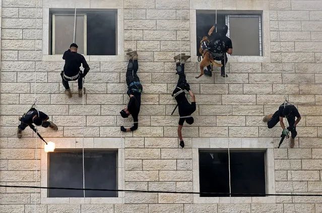 Palestinian members of Hamas' security forces rappel along the wall of a building as they show off their skills during a police graduation ceremony in Gaza City on April 26, 2021. (Photo by Mahmud Hams/AFP Photo)