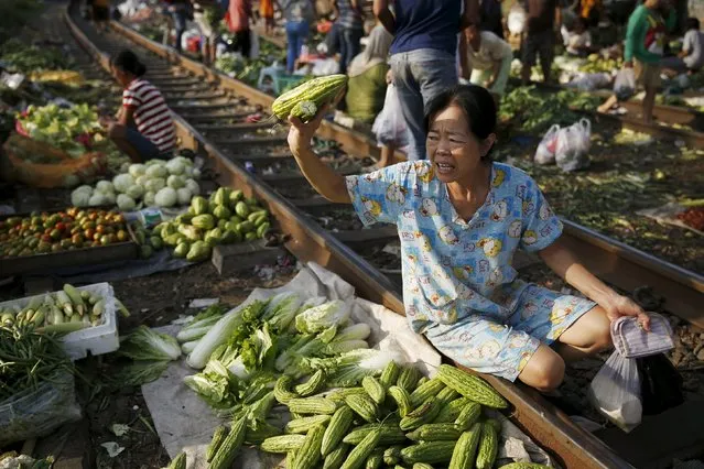 A customer asks for the price of a bittergourd at Duri market on a railway track in Jakarta, January 8, 2016. (Photo by Reuters/Beawiharta)