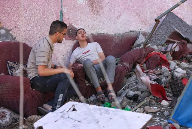Palestinians sit among the rubble of their home that was destroyed during Israeli air strikes in Gaza City, on May 18, 2021. Israel maintained its heaviest-ever bombardment of the blockaded enclave overnight, sending a fireball and a black plume of smoke into the sky following one heavy strike, an AFP journalist reported. (Photo by Mohammed Abed/AFP Photo)