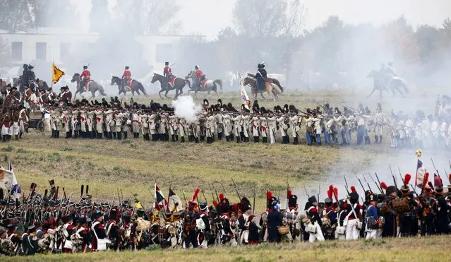 Performers wearing 19th century Allied forces (top) and French forces military uniforms attack one another during a reenactment of the Battle of the Nations, in a field in the village of Markkleeberg near Leipzig October 20, 2013. The east German city of Leipzig commemorated the 200th anniversary of the largest battle of the Napoleonic Wars on Sunday by reenacting the Battle of the Nations, with 6,000 military-historic association enthusiasts from all over Europe. The decisive encounter in which tens of thousands of soldiers were killed, took place from October 17-19, 1813, just outside of Leipzig. At the height of the hostilities Napoleon fielded more than 200,000 men against an Allied force of some 360,000 soldiers which included troops from Russia, Austria, Prussia and Sweden. (Photo by Fabrizio Bensch/Reuters)