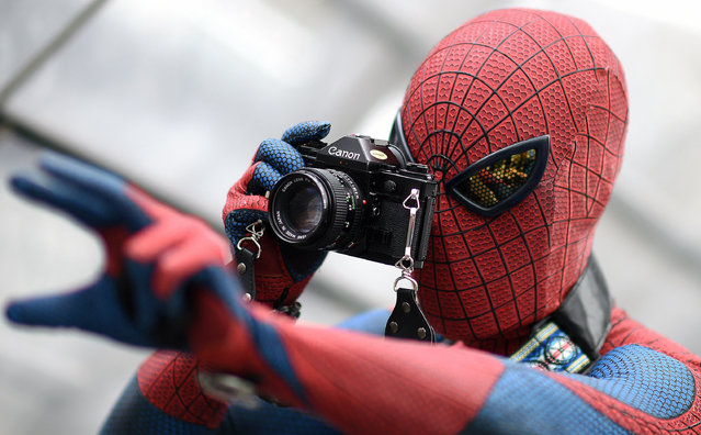 A visitor in a costume of fictional superhero Spiderman takes pictures during the Leipzig Book Fair on March 14, 2015. (Photo by Hendrik Schmidt/AFP Photo/DPA)