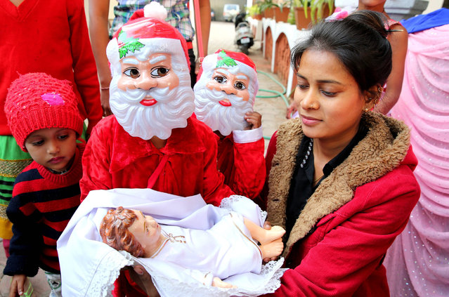 Indian children dressed up as Santa Claus stand next to a crib of infant Jesus during mass prayer at a church in Bhopal, India, 25 December 2016. Although Christians represent only a bit more than two percent of the Indian population, Christmas Day is celebrated throughout the country. (Photo by Sanjeev Gupta/EPA)