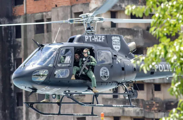 The leader of Brazilian criminal gang Comando Vermelho, Marcelo Pinheiro (2-R), aka “Piloto”, is seen under tight security on a Parana state police helicopter, shortly after leaving the city of Foz do Iguacu, on their way to Catanduvas maximum security federal penitentiary in Parana state, Brazil, on November 19, 2018. After scaping a Brazilian prison where he was serving a 15-year-sentence, Piloto was detained in Paraguay on December 2017. On November 17, 2018 he killed a young woman during a visit in jail, in an attempt to avoid extradition, but Paraguayan President Abdo decided to expell him from the country. (Photo by Christian Rizzi/AFP Photo)