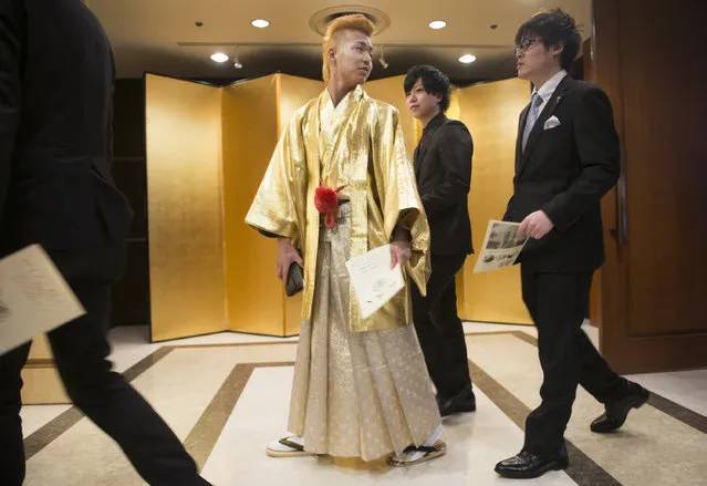 A young man with a gold mohawk in a hakama among others in business suits arrives at the Seijin no Hi (Coming-of-Age) ceremony in Kanazawa, Japan on January 10, 2016. (Photo by Linda Davidson/The Washington Post)