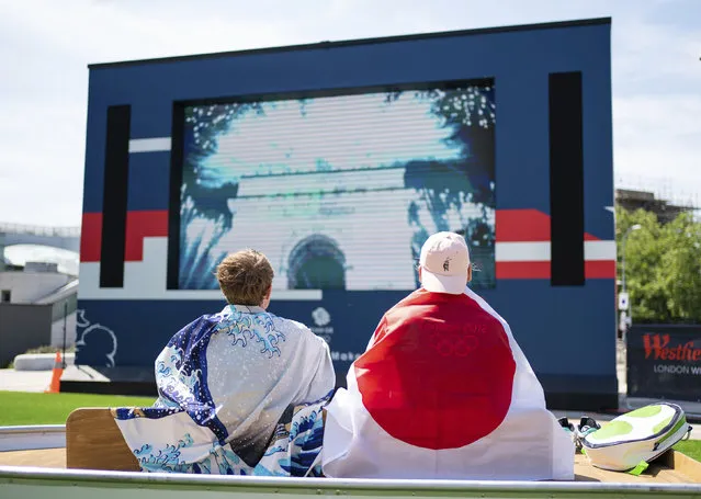 Fans watch the opening ceremony of the Tokyo 2020 Olympic Games on a big screen at the Team GB Tokyo 2020 Olympics fanzone, at Westfield, London, Friday July 23, 2021, which will be open for the next 17 days. (Photo by Dominic Lipinski/PA Wire via AP Photo)