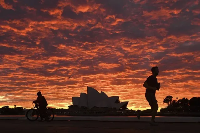 A jogger runs past the Sydney Opera House at dawn in Sydney, Wednesday, July 28, 2021. Australia’s largest city Sydney will remain in lockdown for another four weeks due to a growing COVID-19 cluster. (Photo by Mick Tsikas/AAP Image via AP Photo)