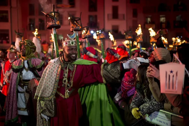 A man dressed as King Balthazar, one of the three wise men or the Three Kings shakes hands during the Three Wise Men Parade (Cabalgata de los Reyes Magos) in Vic on January 5, 2017, marking the eve of the feast of Epiphany This year' s controversial parade in Vic is marked by the Catalan Government' s endorsement that separatist associations can turn the event into a day of protest in favour of independence from Spain' s central government by turning out in large numbers with Catalonia' s pro- independence flag, the “Estelada”. (Photo by Josep Lago/AFP Photo)