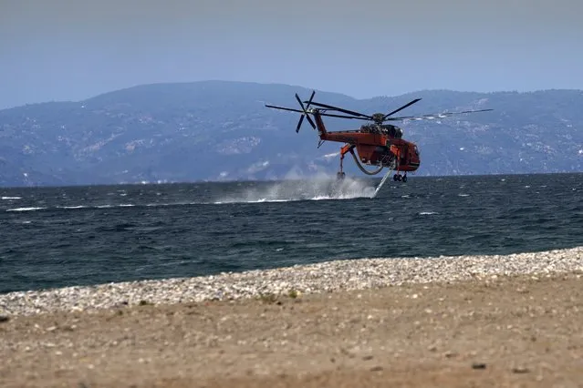 An helicopter fills water during a wildfire at Pefki village on Evia island, about 189 kilometers (118 miles) north of Athens, Greece, Monday, August 9, 2021. (Photo by Petros Karadjias/AP Photo)