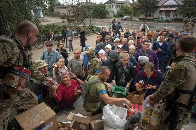 Ukrainian servicemen of Sophia battalion distribute humanitarian aid to local residents in the recently liberated town of Izium, Ukraine, Sunday, October 2, 2022. (Photo by Evgeniy Maloletka/AP Photo)