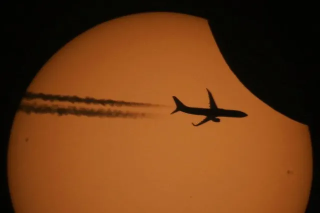 A picture taken through a telescope shows a silhouette of an aircraft against the sun during a partial solar eclipse in the settlement of Kojori outside Tbilisi, Georgia on October 25, 2022. (Photo by Irakli Gedenidze/Reuters)