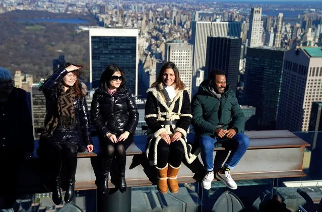 People visit the new interactive experience called “The Beam” at Rockefeller Center on December 12, 2023, allowing visitors to recreate the famed 1932 photo “Lunch Atop a Skyscraper”, showing 11 workers eating lunch on a steel beam above Manhattan while 30 Rock was under construction. Visitors are strapped on a steel beam replica on the 69th floor, then are lifted 12 feet (3.5 meters) above the Observation Deck platform and taken for a 180-degree turn. (Photo by Timothy A. Clary/AFP Photo)