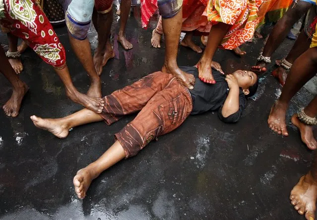Hindu holy men (not pictured) touch a boy with their feet as part of a ritual to bless him during a religious procession to mark the Gajan festival in Kolkata April 13, 2015. (Photo by Rupak De Chowdhuri/Reuters)