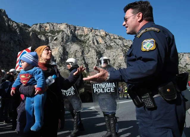 A police officer argues with migrants during a protest on a highway at Tempe valley near the city of Larissa, in central Greece, on Thursday, February 25, 2016. Tougher Balkan border controls have left thousands of people stranded in Greece, where some 4,000 migrants and refugees continue to arrive daily. Police are stopping buses carrying migrants to the border with Macedonia, leaving hundreds stranded stander along the highway between Athens and the northern city of Thessaloniki. (Photo by Giorgos Kydonas/InTime News via AP Photo)